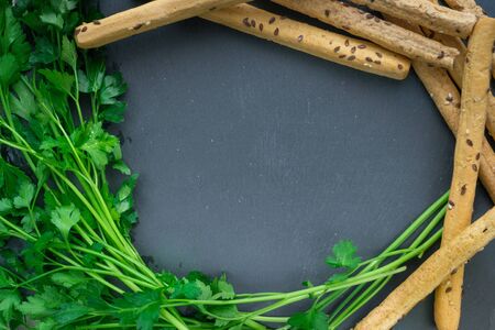 parsley and bread sticks on black background for designの写真素材