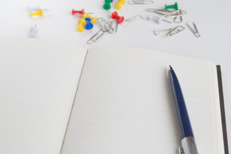 pen on the open notebook for writing text on a background paper clip