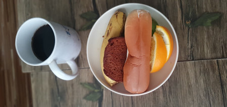 A cup of coffee and a sausages in a bowl on a wooden tableの写真素材