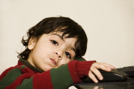 a cute little boy eating cookies and working on his PC の写真素材