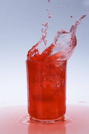 red juice splashing out of a glassの写真素材