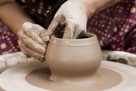female potter s hands shaping up the terracotta clay pot on wheal  の写真素材