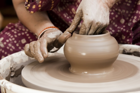 female potter s hands shaping up the terracotta clay pot on wheal  の写真素材