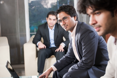 confident indian businessman with his colleagues in the backgroundの写真素材
