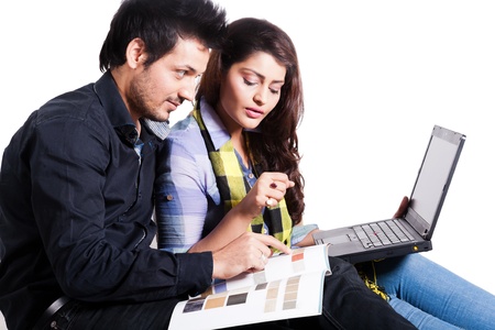 young couple selecting the flooring for the new home,happy young couple using laptop isolated on white, multi ethnic couple isolated on white の写真素材