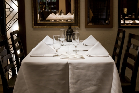 close of a dining table in a restaurant with white napkins and wine glasses.の写真素材