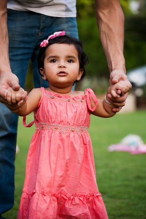 father helping his daughter to take first step of lifeの写真素材