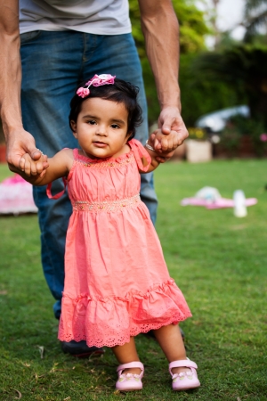father helping his daughter to take first step of lifeの写真素材