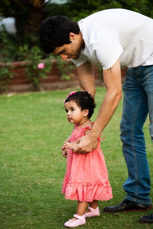 father helping his daughter to take first step of lifeの写真素材