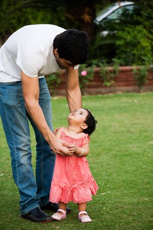 father helping his daughter to take first step of lifeの写真素材