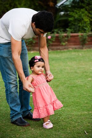 father helping his daughter to take first step of lifeの写真素材