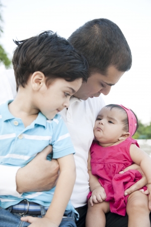 little baby girl and a little boy sitting in the lap of the fatherの写真素材