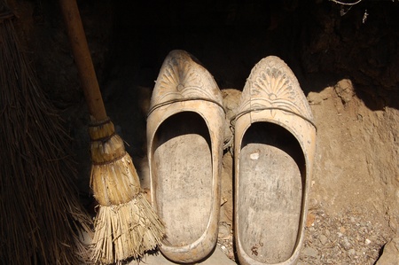 Half-lighted wooden shoes at the entrance of a rural house