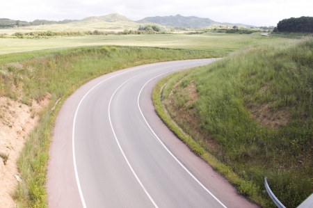 Curve in a road crossing green cereal fieldsの写真素材