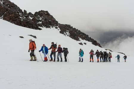 Caucasus / Russia - 02/06/2008 Group of climbers, acclimatization program in the mountains before climbing Mount Elbrus. Tourists take pictures on the background of high snowy mountain peaks.のeditorial素材