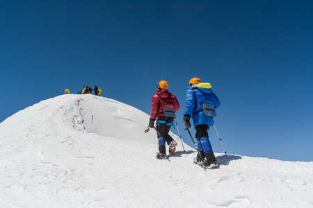 Caucasus / Russia - 02/06/2008 Group of climbers, acclimatization program in the mountains before climbing Mount Elbrus. Tourists take pictures on the background of high snowy mountain peaks.のeditorial素材
