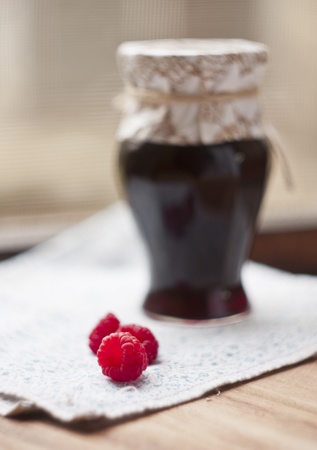 jar of raspberry jam, three fruit in front,