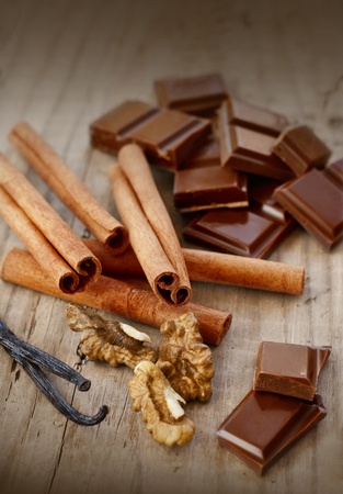 confectionary products  Chocolate, cinnamon, walnuts and vanilla on wooden tableの写真素材