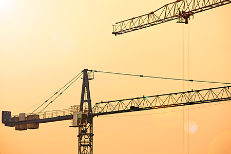 Abstract Industrial background with construction cranes silhouettes over amazing sunset skyの写真素材