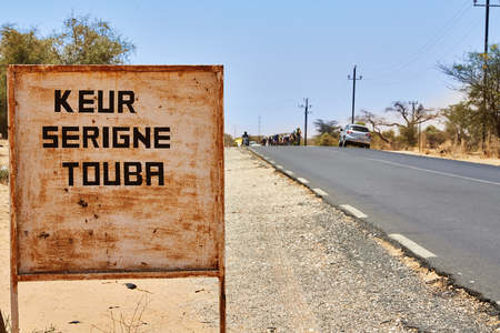 signpost to touba in senegal, background blurry desert landscapeの写真素材