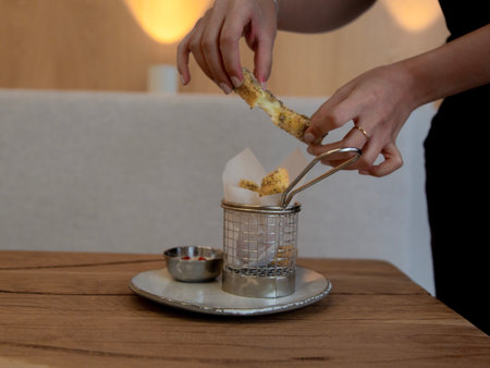 Female hands with tongs making a toast on a wooden table.