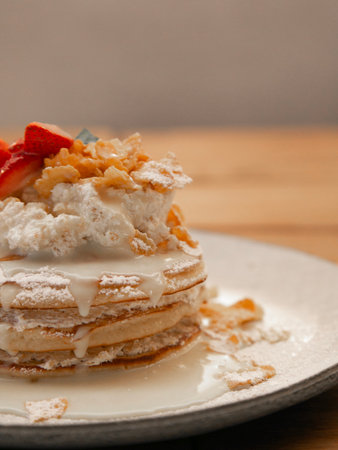 Pancakes with whipped cream and strawberries on a white plate.