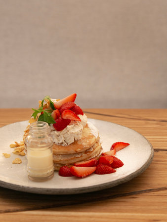 Pancakes with fresh strawberries and whipped cream on a white plateの写真素材