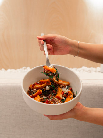 quinoa bowl topped with roasted pumpkin slices, creamy feta cheese, crunchy toasted pecans, fresh...