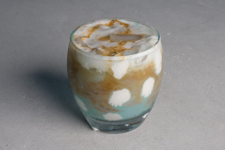 Coffee with milk in a glass on a gray background.