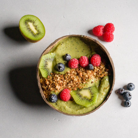 Healthy breakfast bowl with oat granola, kiwi, blueberries and raspberries