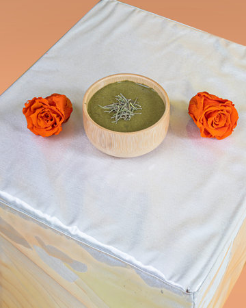 Wooden bowl with matcha tea on white tablecloth and orange rosesの写真素材