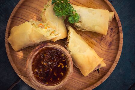 Asian food spring rolls on a timber plate and sauce