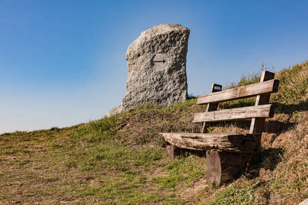 A wooden bench and a granite sign invite you to restの写真素材