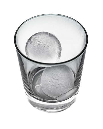 Side view in black and white of a tapered glass with two round ice cubesの写真素材