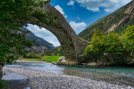 Roman bridge over river of rapid water in pyreneesの写真素材