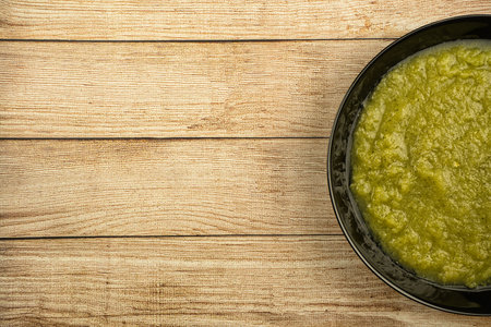 a black plate of fresh vegetable green cream soup served on rustic background, foodの写真素材