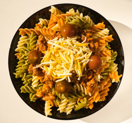 a black plate of fresh italian boiled pasta fusilli with meat, tomatoes and cheese served on a withe table, italian foodの写真素材