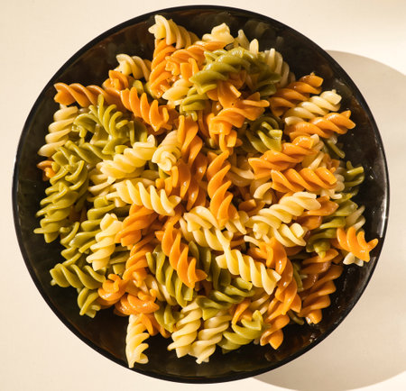 a black plate of fresh italian boiled pasta fusilli served on a withe table, italian foodの写真素材