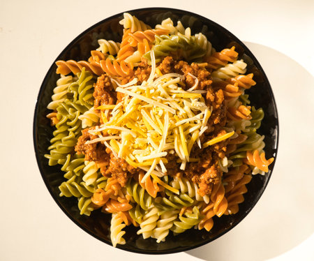 a black plate of fresh italian boiled pasta fusilli with meat and cheese served on a withe table, italian foodの写真素材