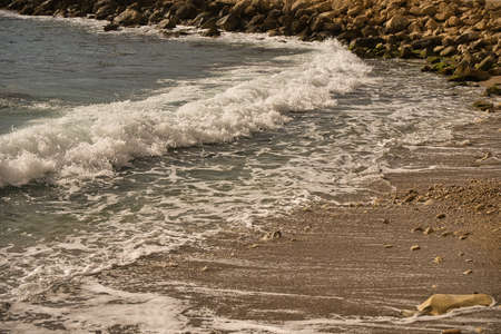 Sea waves lash line impact rock on the beach, located in Alicante, Spainの写真素材