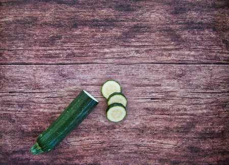 Fresh vegetable detox soup made from peas in a plate on brown wooden table with cucumbers and green pepper, top view with space for text. Tastyの写真素材