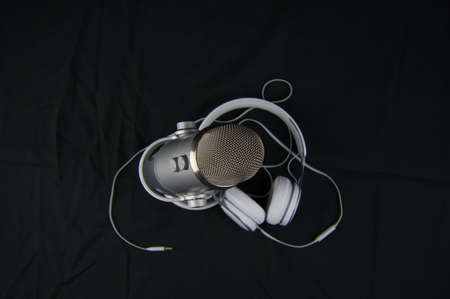 studio microphone and headphones for recording podcast on black background. object