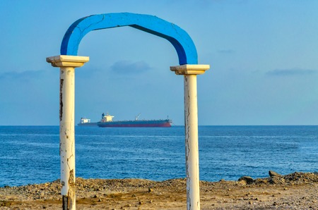 Two ships framed by an old, ruined arch on the beach.の写真素材