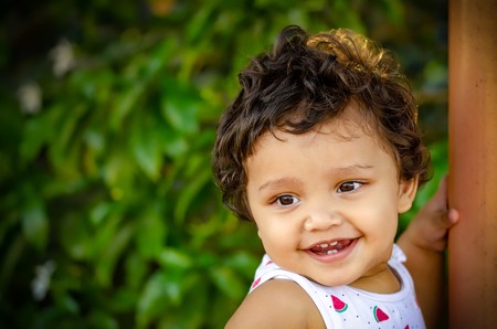Closeup portrait of a happy Indian girl in the park with green background.の写真素材