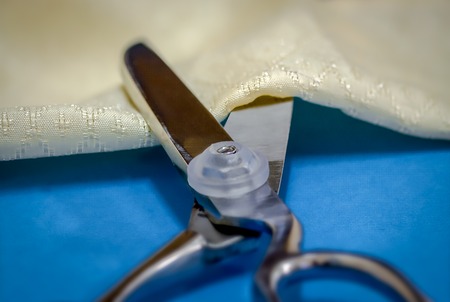 Closeup of scissors ready to cut through the fabric placed between its sharp blades. Macro shot.