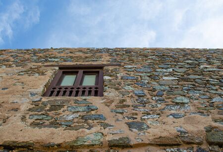 Wooden window on a stone wall of the historic Muttrah Fort in Muscat, Oman. Low angle view.の写真素材