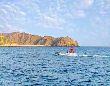 Speed fishing boat moving right next to a red buoy near Muttrah Port, Muscat, Oman.の写真素材