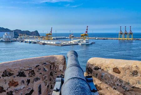 Old cannon on the fort watch tower pointing towards the port and the sea with blue sky background. From Muscat, oman.の写真素材