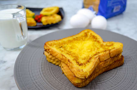 Beautifully Stacked French Toast in a plate along with milk, eggs, bread packetの写真素材