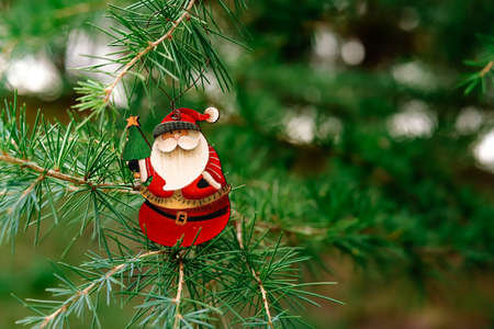 New Year's toy in the form of a snowflake with Santa Claus hangs on the Christmas tree. Close-up,...